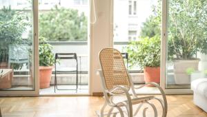 a rattan chair sitting in a room with plants at Athenian Blue - Family Apt 5' Minutes from Acropolis Museum in Athens