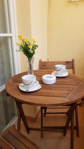 a wooden table with two bowls and a vase with flowers at Apartamento Nerja Beach in Nerja