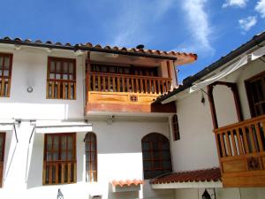 a white house with a wooden balcony at Quinua Boutique Apartments in Cusco