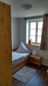 een kleine slaapkamer met een bed en een raam bij Ferienwohnungen Mühlenhof Oberseifersdorf in Mittelherwigsdorf