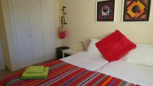 a bedroom with a bed with red and green pillows at Duquesa Village in Manilva