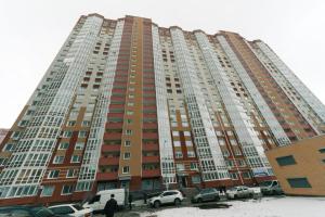 Cozy Apartment on Gmyri 12b near metro Poznyaki في كييف: مبنى كبير فيه سيارات تقف امامه