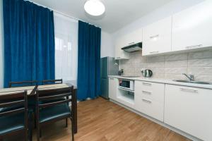 Cozy Apartment on Gmyri 12b near metro Poznyaki في كييف: مطبخ بدولاب بيضاء وستارة زرقاء