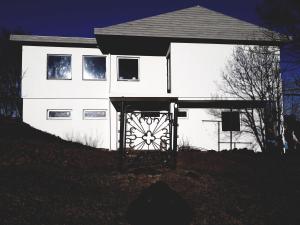 a white house with a gate in front of it at Guesthouse Geldingaholt in Árnes