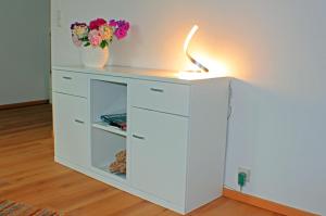 een witte kast met een lamp en bloemen erop bij Wohnen am Roseneck in Berlijn