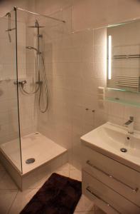 een witte badkamer met douche en wastafel bij Wohnen am Roseneck in Berlijn