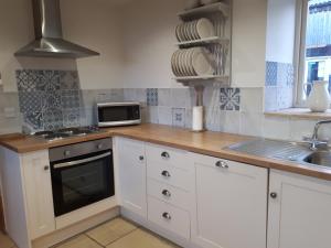 una cucina con armadi bianchi, lavandino e forno a microonde di Meadowbeck Holiday Cottages a Whitby