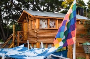 a log cabin with a colorful umbrella in front of it at Infinito Chill0ut in San Marcos Sierras
