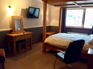 a bedroom with a bed and a mirror and a chair at Hillview Park in Beauly