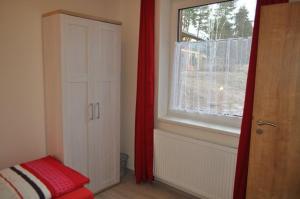 a bedroom with a window and a red curtain at Moderni Domek Lipno in Lipno nad Vltavou