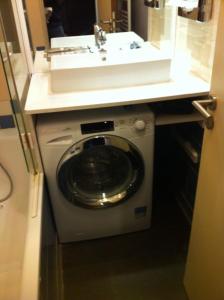 a washing machine under a sink in a bathroom at Aparthotel Paris 15 Porte de Versailles in Issy-les-Moulineaux