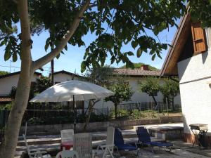 Una mesa con sillas y una sombrilla en un patio. en Villino Colussi, en Lignano Sabbiadoro