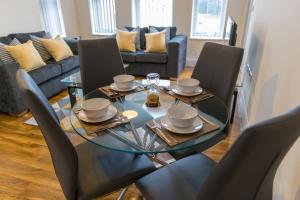 een eetkamer met een glazen tafel en stoelen bij London Heathrow Serviced Apartments in Stanwell