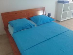 a bed with blue sheets and blue pillows at Location bas de maison in Sainte-Anne