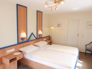 1 dormitorio con 1 cama blanca grande y cabecero de madera en Bungalow *Ual Welhüs*, en Norddorf