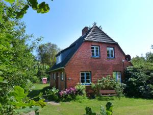 una casa de ladrillo rojo con un banco en el patio en Ferienhaus *Koggenhüs* en Norddorf