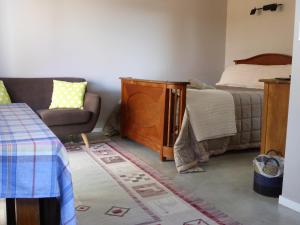 a bedroom with a bed and a couch and a chair at Bungalow on Bell Common in Tauranga