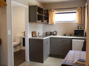 a small kitchen with a sink and a toilet at Bungalow on Bell Common in Tauranga +6 photos