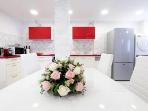 a white kitchen with a table with a bouquet of flowers at FaRoyal Luxury Suite in Eilat