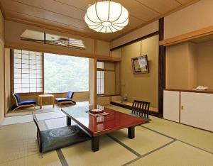 Marumine Kanko Hotel في أيزواكاماتسو: غرفة معيشة كبيرة مع طاولة وكراسي