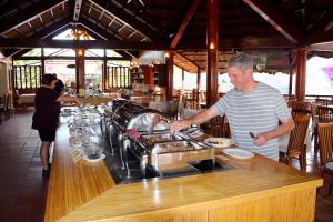 Little Muine Cottages Resort في موي ني: رجل يعد الطعام في كونتر في مطعم