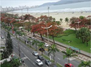 a busy city street with cars parked on a road next to a beach at Apartamento Gonzaga in Santos