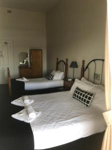 two beds in a room with a white bedspread at Grosvenor Hotel in Victor Harbor
