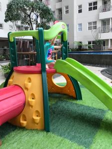 un niño jugando en un tobogán en un parque infantil en Sam’s Parahyangan Residence en Bandung