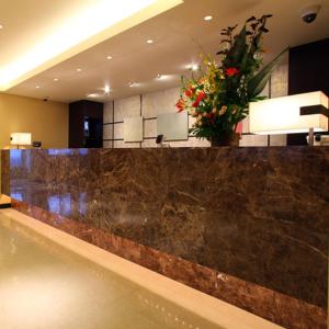 un vestíbulo con un mostrador de mármol con un jarrón de flores en Hotel Housen Soka, en Soka