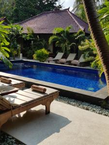 a swimming pool with lounge chairs next to a house at Senang Villa by Ambassador in Gili Islands