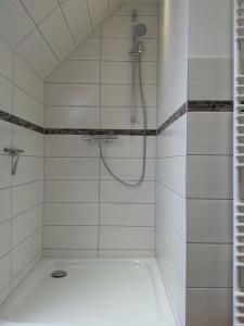 a white tiled shower with a shower head at Ostseebrise-Fehmarn in Fehmarn