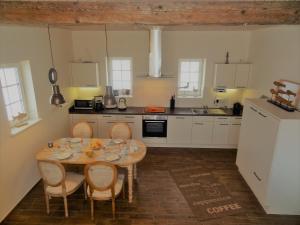 a kitchen with a table and chairs and a kitchen with white cabinets at Weitblick in Hasselberg