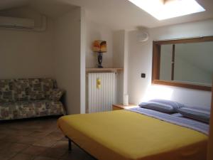 a bedroom with a yellow bed and a couch at A Casa da Franz in Manerba del Garda