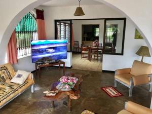 a living room with a large screen tv in a room at Tradewinds Lodge in Diani Beach