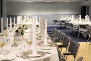 una mesa larga con mesas blancas y sillas en una habitación en Tambohus Kro & Badehotel, en Hvidbjerg