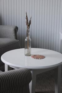Una mesa blanca con un jarrón encima. en Tambohus Kro & Badehotel en Hvidbjerg
