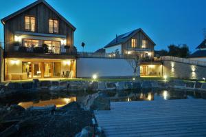 uma casa com um lago em frente à noite em Chalets Petry Spa & Relax em Bettel