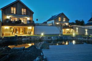 a house with a pond in front of it at night at Chalets Petry Spa & Relax in Bettel