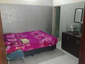 - une chambre avec un lit violet et une commode dans l'établissement Griya Palayu, à Bogor