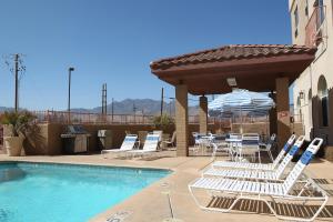 eine Gruppe Stühle und ein Pool mit Sonnenschirm in der Unterkunft Garden Place Suites in Sierra Vista