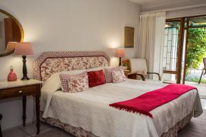 a bedroom with a bed with a red blanket on it at Milkwood Country Cottage in St Francis Bay