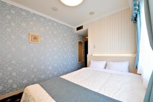 Hotel Paco Obihiro Ekimae في أوبيهيرو: غرفة نوم بسرير وجدار ازرق