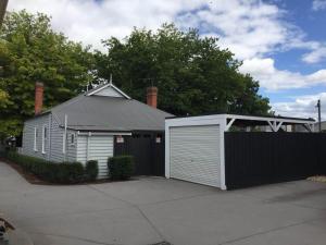 a house with a white garage and a black fence at Magnolia Cottage in Healesville