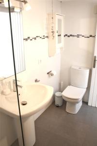a white bathroom with a toilet and a sink at Lovely villa next to the beach in Cambrils