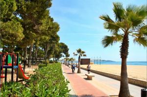 a park with a playground and a beach with palm trees at Lovely villa next to the beach in Cambrils
