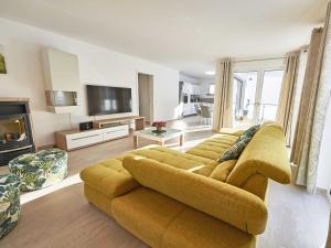 a living room with a yellow couch and a television at Haus Kap Arkona in Sellin - Fewo 02 mit Kamin und Terrasse in Ostseebad Sellin