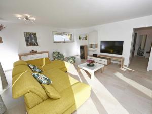 a living room with a yellow couch and a tv at Haus Kap Arkona in Sellin - Fewo 02 mit Kamin und Terrasse in Ostseebad Sellin +17 photos