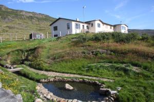 una casa en la cima de una colina con un arroyo en Hótel Laugarhóll with natural hot spring, en Hólmavík