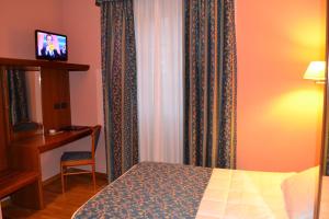 a bedroom with a bed and a desk and curtains at Albergo Italia in Varallo