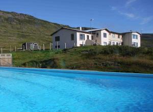 a blue swimming pool in front of a house at Hótel Laugarhóll with natural hot spring in Hólmavík